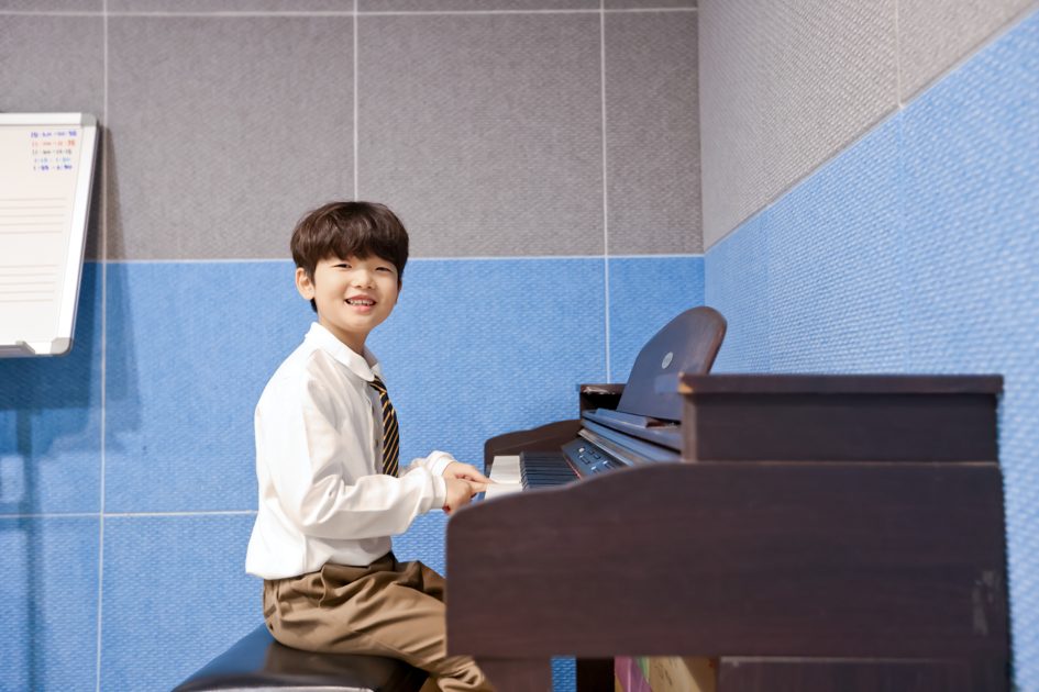 피아노 앞에 앉아 웃는 아이